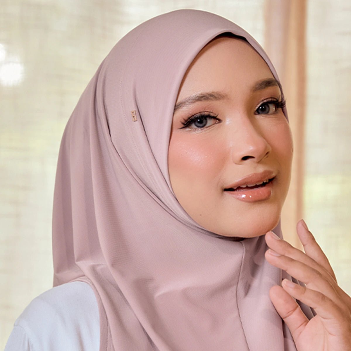 Woman wearing a light pink hijab against a neutral background