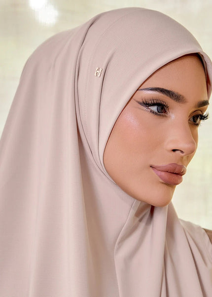 Woman wearing a beige hijab with a soft, blurred background