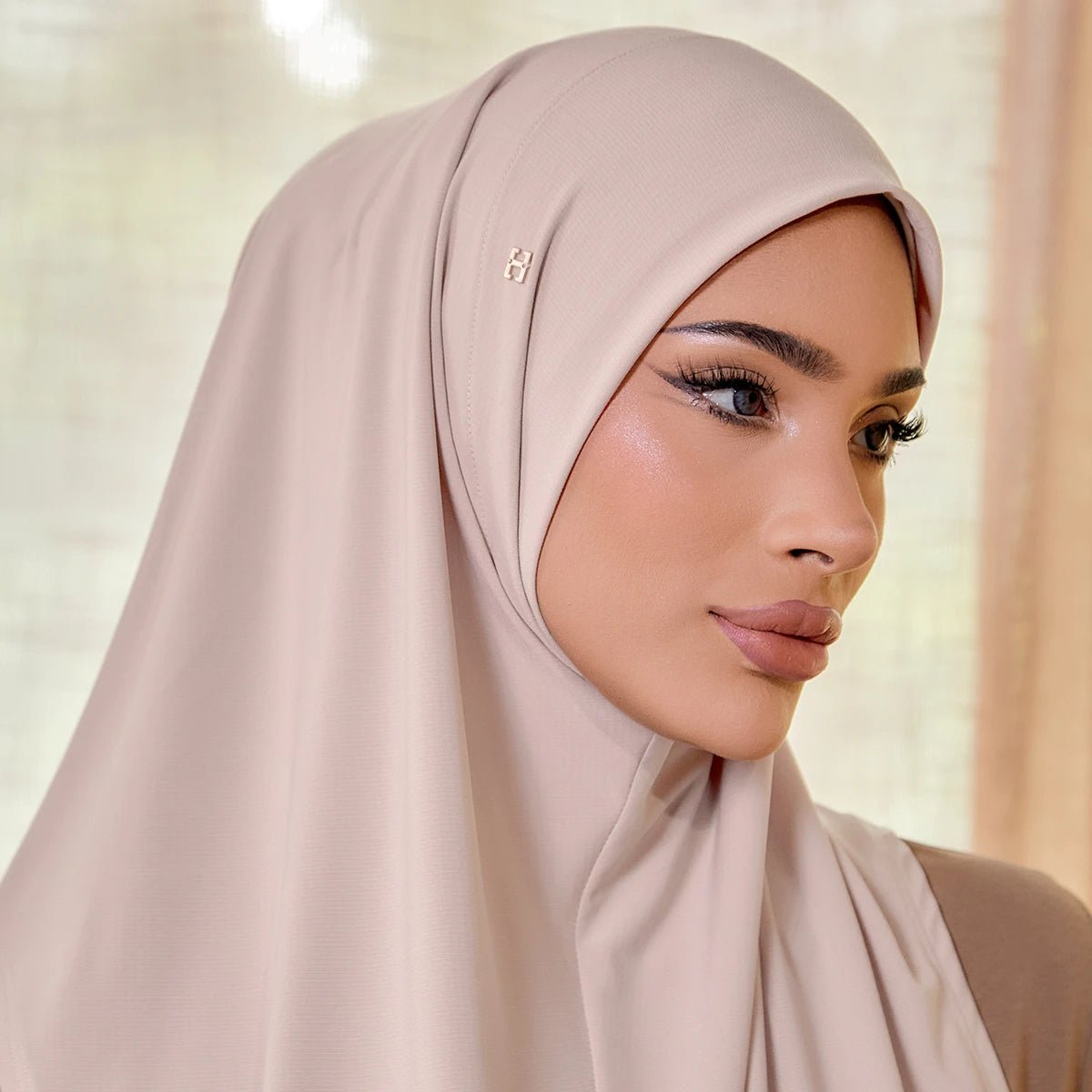 Woman wearing a beige hijab with a soft, blurred background