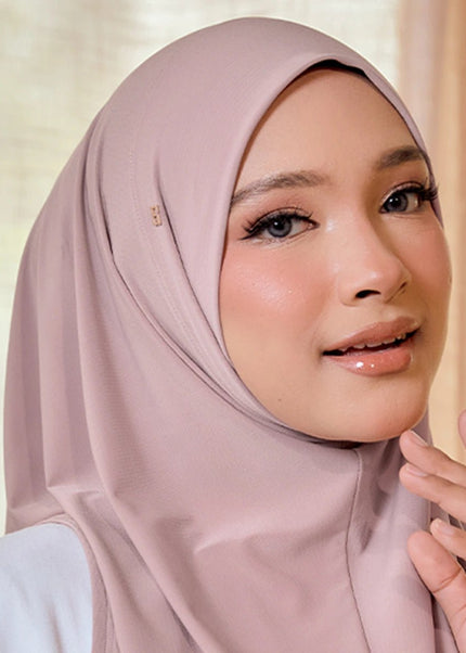 Woman wearing a light pink hijab against a neutral background